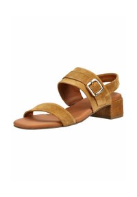 Brun ruskindsandal med åben tå, brede stropper foran og om anklen, sølvspænde og lav blokhæl på hvid baggrund.