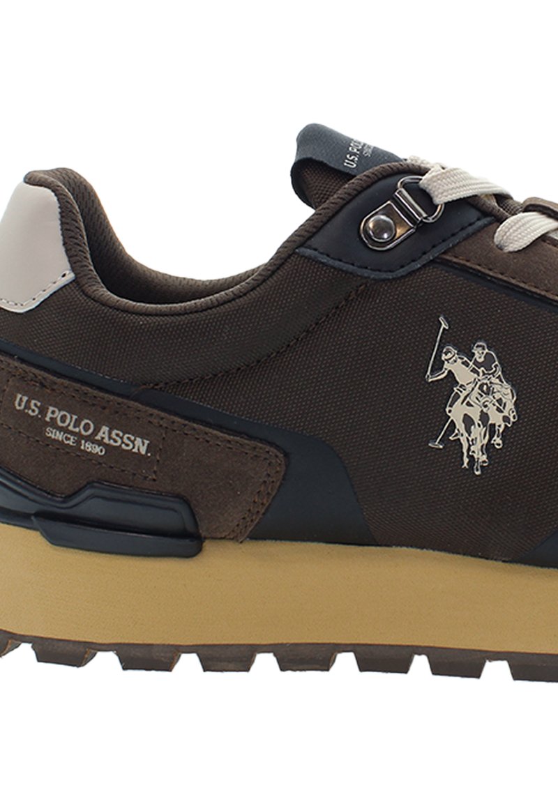 Brązowe sneakersy U.S. Polo Assn. z beżową podeszwą, beżową łatą na pięcie, białymi sznurowadłami, metalowym oczkiem i logo gracza polo z boku.