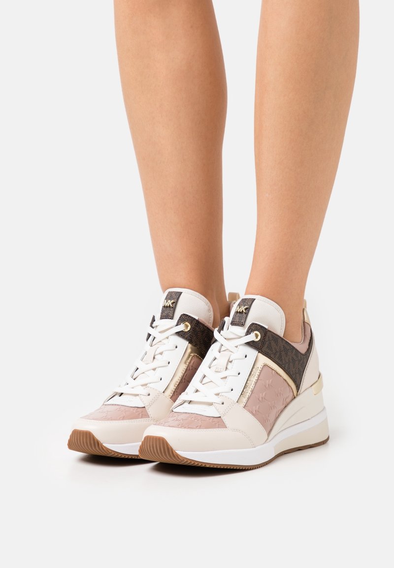 Sneakers bianchi e rosa con pannelli testurizzati, un accento metallico e suola a zeppa, caratterizzati da un design alto e chiusura con lacci.