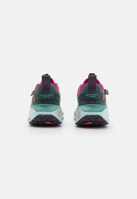 Teal spalvų Gore-Tex bėgimo batai, su rožiniu apvadu ir akcentais. Tamsiai violetinė pado spalva su raudonu akcentu ir kilpos elemento ant kulno.