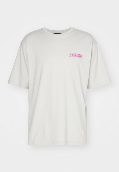 Camiseta de algodón de color claro con mangas cortas y cuello redondo. Muestra un pequeño gráfico en rosa y azul que dice "World Tour" en el pecho.