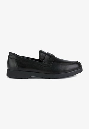 Mocasines de cuero negro con perfil bajo, con una tira decorativa en la parte superior, suela de goma y textura suave.