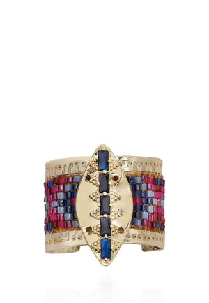 Gold cuff bracelet with central oval plate featuring vertical row of dark blue gems, surrounded by multicolored small rectangular beads in red and blue.
