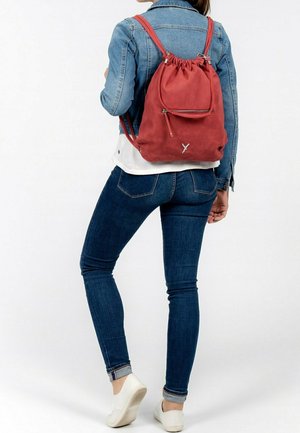 Zaino con coulisse rosso realizzato in tessuto strutturato. Presenta una tasca frontale con zip e spallacci regolabili, con un semplice logo sulla parte anteriore inferiore.