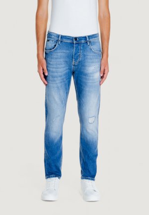 Jeans da uomo in denim blu con finitura sbiadita, leggera usura, design a cinque tasche e taglio dritto, indossati con sneakers bianche.