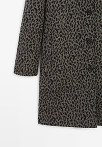 Leopard print coat made of textured fabric. Gray background with black spots, featuring a pointed collar and button closure.
