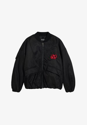 Mustarjakas, mis on valmistatud sarnase materjaliga kui satiin, esiküljel on lukk, ribaga krae ja vasakul küljel on punane tikand.