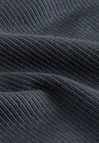 Tessuto grigio scuro con una trama testurizzata a costine, che mostra un aspetto morbido e intrecciato con fibre sottili. Ideale per abbigliamento o accessori.