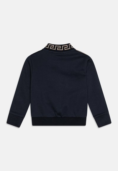 Mørkeblå sweatshirt med lange ermer, ribbede mansjetter og en mønstret svart og gull krage. Mykt stoff, tettsittende design.