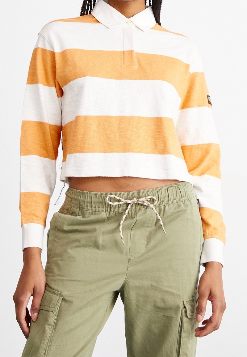 Gestreiftes Langarm-Poloshirt in Orange und Weiß mit Kragen und Knopfleiste, kombiniert mit olivgrünen Cargo-Hosen mit Kordelzug.