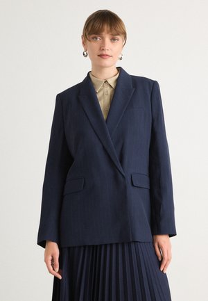 Námořnický blazer s pruhy a klopovými límci, se dvěma předními kapsami a volným střihem, doplněný světlým béžovým košilí s límcem.