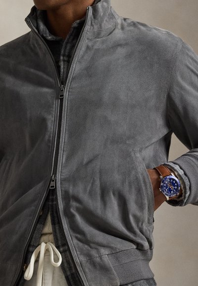 Γκρι σατέν μπουφάν με φερμουάρ στο μπροστινό μέρος, όρθιο γιακά και πλαϊνές τσέπες. Διαθέτει ριμπ μανσέτες και εσωτερική επένδυση με σχέδιο.