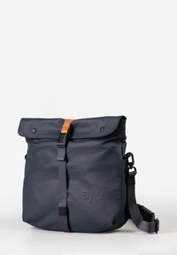 Zaino navy blue a roll-top realizzato in materiale resistente all'acqua, dotato di una tracolla in pelle beige, spallaccio grigio regolabile e dettaglio del logo.