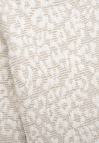 Texturiertes Gewebe mit einem weißen und hellbeigen Leopardenmuster, hergestellt aus weichem Material, mit einer plüschigen Oberfläche und subtiler Glanz.