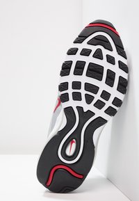 Šedá běžecká bota s texturovanou černou gumovou podrážkou a červenými akcenty. Má vlnitý design a viditelné logo značky na mezipodešvi.