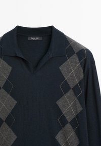 Námořnický pulovr s véčkovým výstřihem a krátkým límcem, zdobený šedými kosočtverci a světlými stehy na měkké pletenině.