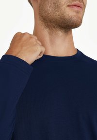 Marineblaues Langarmshirt aus weichem Stoff, mit Rundhalsausschnitt und umgenähten Ärmeln. Minimalistisches Design ohne sichtbare Logos.