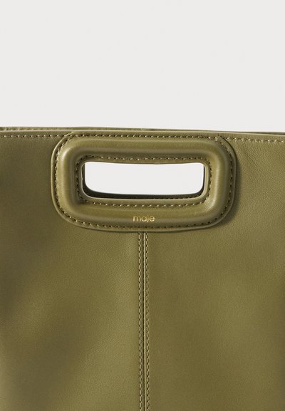 Olivi vihreä nahkalaukku, jossa on suorakulmion muotoinen leikkaus kahvassa. Ominaisuuksiin kuuluvat siistit linjat, näkyvät tikkausviivat ja logon painatus kahvassa.