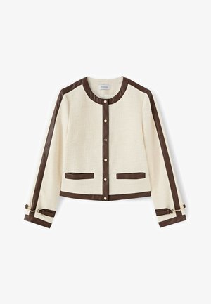 Krémová bunda s texturou a tmavě hnědým lemem podél límce, přední části, rukávů, kapes, spodního lemu a detailů přezek na manžetách, zapínání na knoflíky.