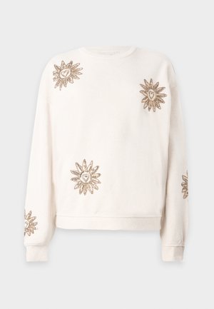 Sweatshirt crème à manches longues, ornée de soleils dorés brodés avec des cœurs en leur centre, poignets côtelés et encolure arrondie.