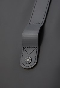 Czarny pasek wykonany z teksturowanego materiału, ozdobiony przeszyciami oraz metalowym okrągłym akcentem z motywem gwiazdy.