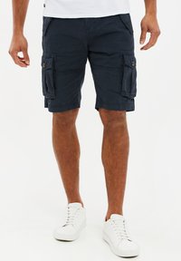 Pantaloni cargo navy in cotone, con due grandi tasche laterali, cuciture a contrasto e vestibilità rilassata. Abbinati a sneakers bianche.