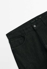 Jeans in denim nero con design classico a cinque tasche, chiusura con bottone in metallo e linee pulite con una finitura leggermente testurizzata.