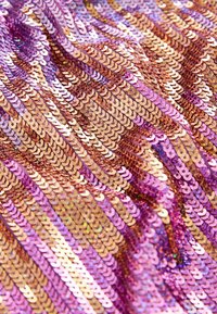 Pailletestof med pink og guld pailletter arrangeret i bølgede mønstre. Overfladen har en blank, reflekterende tekstur med varierende lyseffekter.