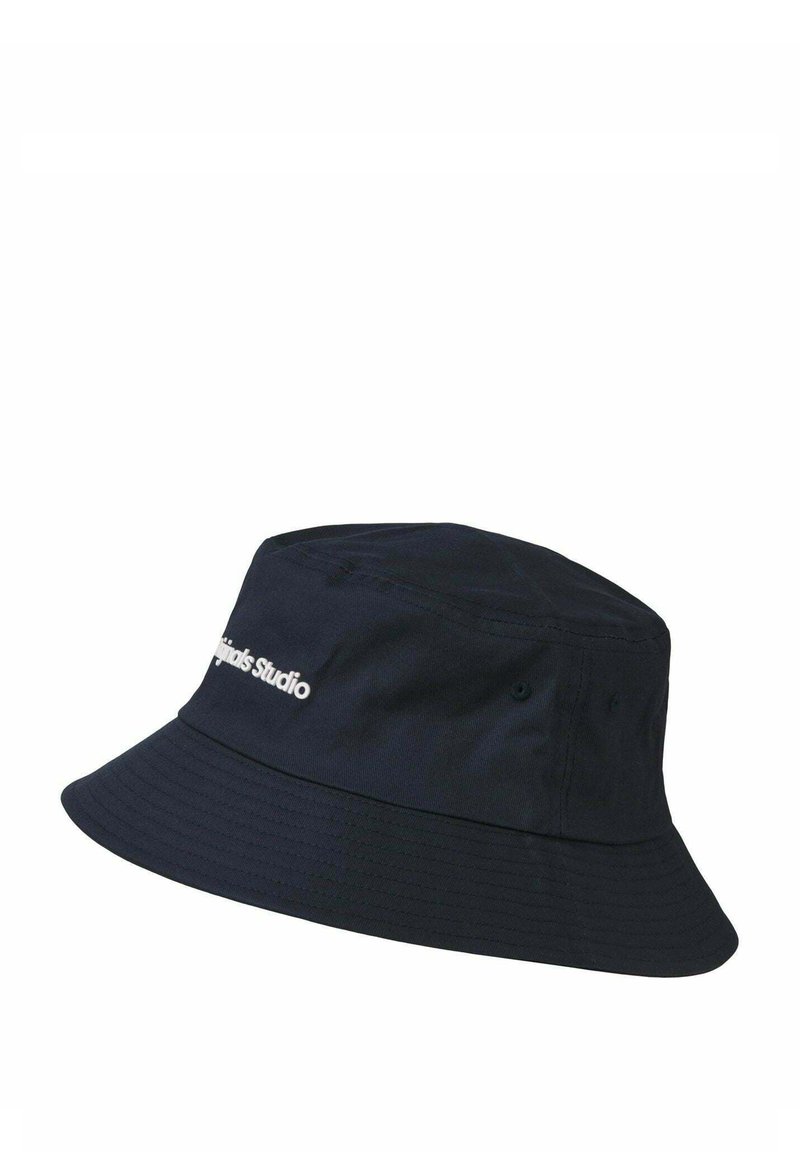 Marineblauwe bucket hat van stof, met een brede rand, twee ventilatieoogjes en een wit "Studiopins" logo op de voorkant.
