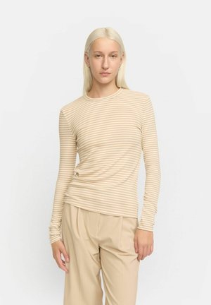Camicia a maniche lunghe a righe in tonalità beige. Realizzata in tessuto morbido con scollatura rotonda e design aderente. Abb binata a pantaloni beige chiari.