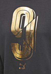 Sweat-shirt noir avec un grand graphique doré métallique du chiffre 9, au design stylisé, avec un petit logo Puma en bas.
