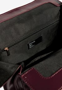 Burgundijas ādas rokassoma ar rāvējslēdzēja kabatu, melnu auduma oderi un birku ar tekstu "tādi draugi..." baltā krāsā.