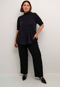 Top negru, cu mânecă scurtă, cu un gât înalt, având un finisaj texturat. Împerecheat cu pantaloni negri largi și pantofi negri cu vârf ascuțit.