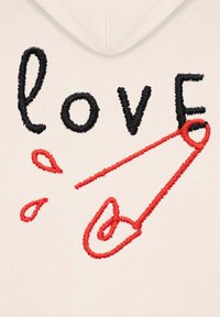 Felpa chiara con cappuccio, con testo ricamato in nero e rosso che spellano "love", dotata di una spilla di sicurezza rossa e due gocce vicino al fondo.