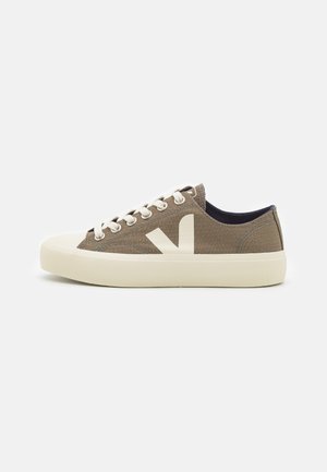 Sneakers in tela marroni con una finitura testurizzata, lacci crema e un grande logo bianco. Suola in gomma con un design leggermente elevato.