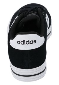 Sneaker en suede noir avec un empiècement en cuir blanc au talon et trois rayures blanches. Doté d'une languette texturée et de lacets noirs. Semelle intermédiaire blanche avec des accents noirs.