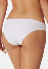 Slip da bikini in cotone bianco con una superficie liscia, taglio a vita bassa e cintura elastica con dettagli di cucitura minimi.