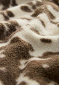 Brown and cream fleece fabric with a wavy texture, featuring a mottled pattern of irregular spots in varying shades of brown.