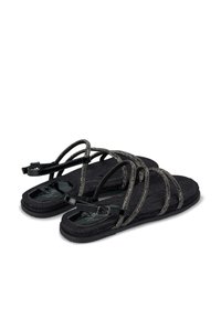 Schwarze Sandalen mit strukturierten Stoffriemen und metallischen Akzenten, flacher Sohle und einer verstellbaren Schnalle für eine sichere Passform.