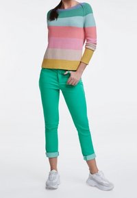 Maglione a righe in rosa, blu e giallo; pantaloni verdi corti; sneakers bianche. Materiale morbido a maglia, vestibilità comoda, stile casual.