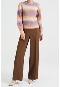 Pull en maille avec des nuances dégradées de violet et de pêche, présentant une texture côtelée et des manches bouffantes, associé à un pantalon large marron.