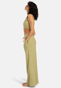 Haut de crop vert clair et pantalon large en tissu doux et texturé. L'ensemble comprend des poches latérales et une taille avec cordon de serrage.