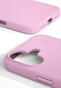 Nærbillede af to matte lyserøde mobiltelefonetuier med udskæringer til kamera, knapper og opladningsport, mærket "Ideal of Sweden".