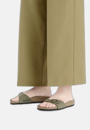 Sandali Birkenstock verde oliva con una suola in sughero testurizzato, fibbia regolabile e un design morbido per l'area delle dita.