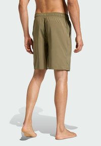 Olivově zelené plavkové šortky vyrobené z lehké tkaniny, s elastickým pasem, bočními kapsami a uvolněným střihem sahajícím ke kolenům.