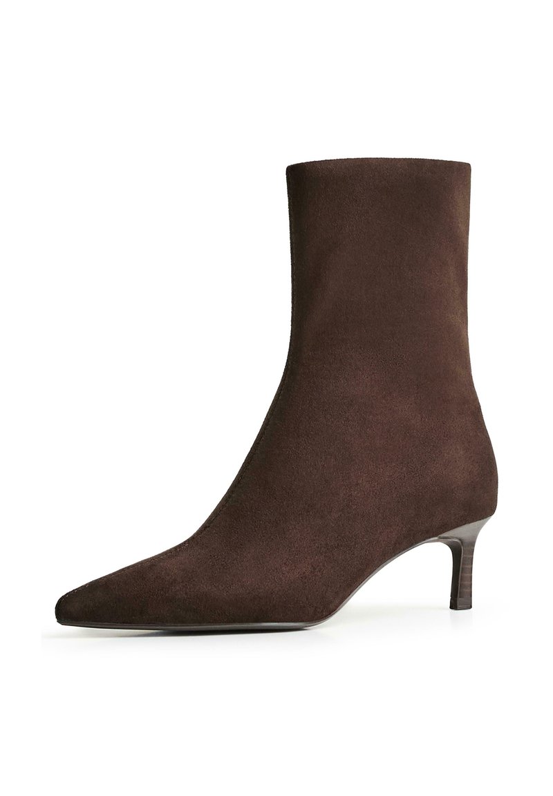 Bocanc maro din suede, la gleznă, cu vârf ascuțit și toc subțire, jos. Textură netedă, cu un design fără cusături și fără hardware vizibil.