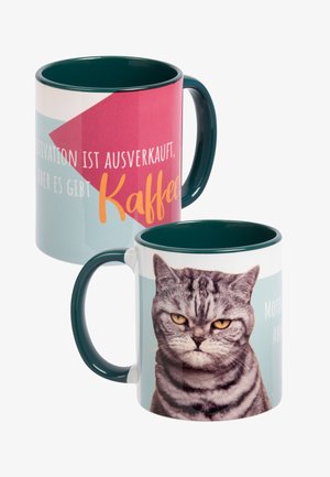 Keramiktasse mit einem türkisfarbenen Innenraum und Griff. Auf einer Seite befindet sich ein Bild einer grauen Katze, während die andere bunte Texte und Formen zeigt.