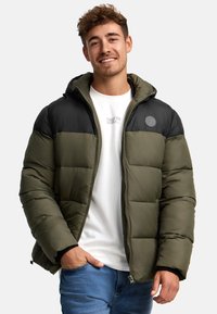 Puffjakke med en sort overdel og olivengrøn underdel, med lynlås lukning og sidelommer. Struktureret, quiltet design.