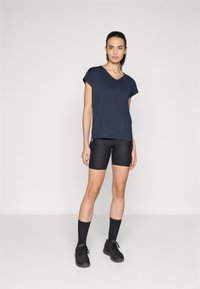 Marinblå V-ringad t-shirt med korta ärmar, tillsammans med högmidjade svarta cykelshorts med leopardmönster. Stylad med svarta träningsstrumpor och skor.