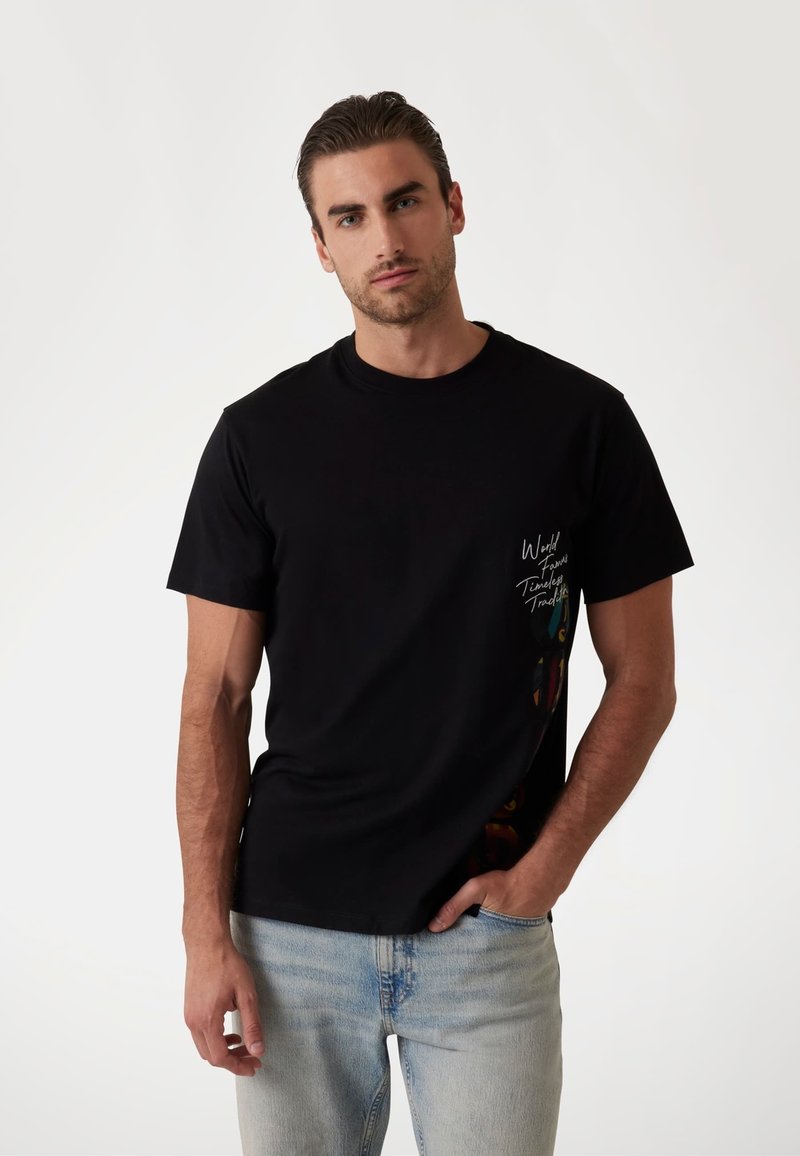 Sort bomulds t-shirt med rund halsudskæring og korte ærmer, med hvid tekst på forsiden og farverigt grafisk design på siden.